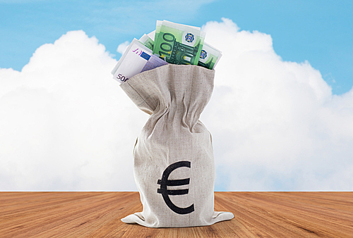 business, finance, investment, saving and cash concept - close up of euro paper money in bank bag over blue sky and wooden floor background