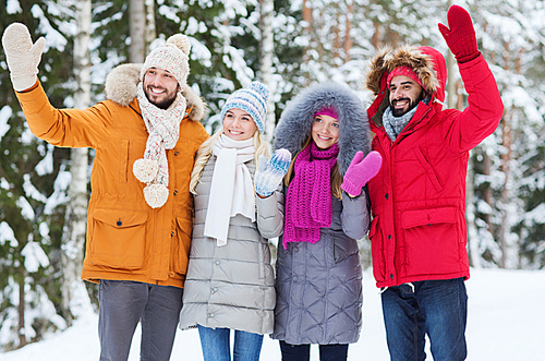 love, relationship, season, friendship and people concept - group of smiling men and women waving hands in winter forest