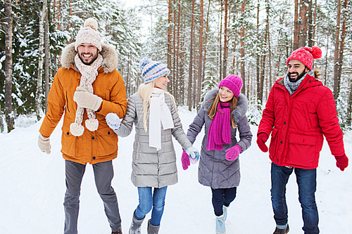 love, relationship, season, friendship and people concept - group of smiling men and women walking ad having fun in winter forest