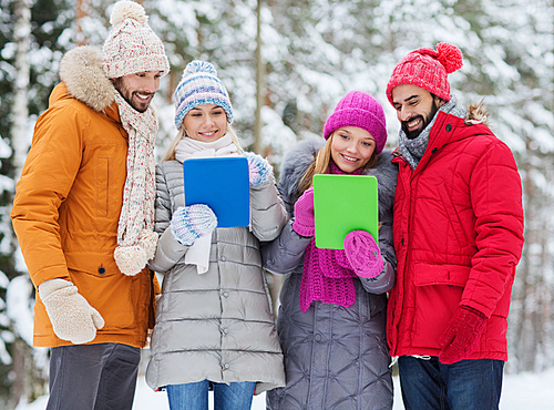 technology, season, friendship and people concept - group of smiling men and women with tablet pc computers in winter forest