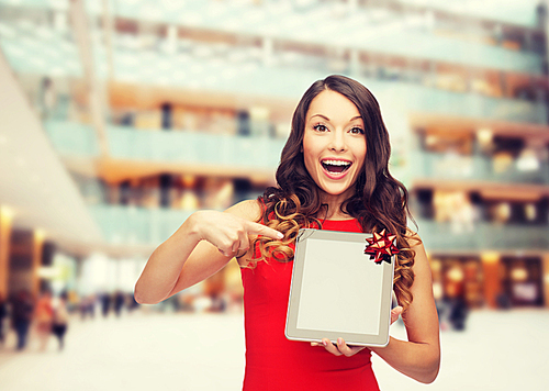 christmas, technology, present and people concept - smiling woman in red dress with blank tablet pc computer screen over shopping centre background