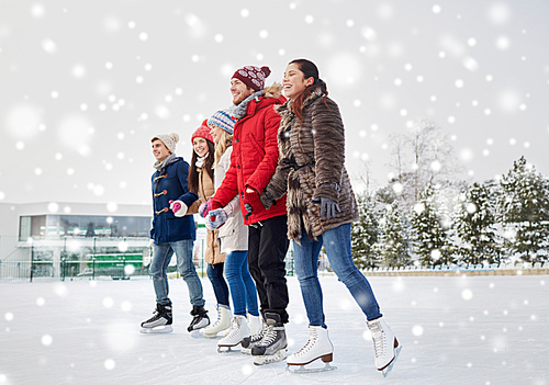 people, winter, friendship, sport and leisure concept - happy friends ice skating on rink outdoors