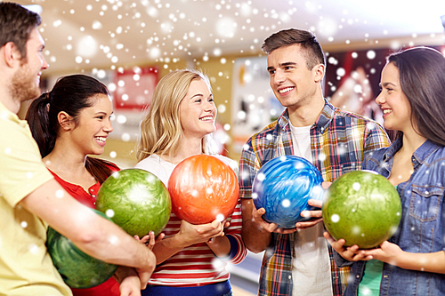 people, leisure, sport, friendship and entertainment concept - happy friends in bowling club at winter season