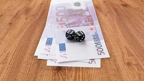 casino, gambling and fortune concept - close up of black dice and euro cash money on wooden table background