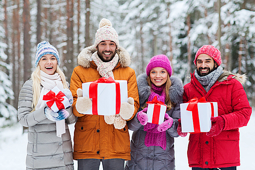 holidays, christmas, season, friendship and people concept - group of smiling friends with gift boxes in winter forest