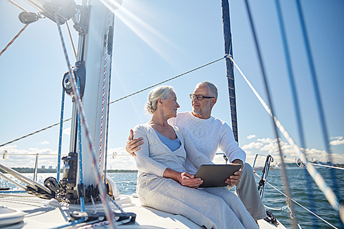 sailing, technology, tourism, travel and people concept - happy senior couple with tablet pc computer talking on sail boat or yacht deck floating in sea