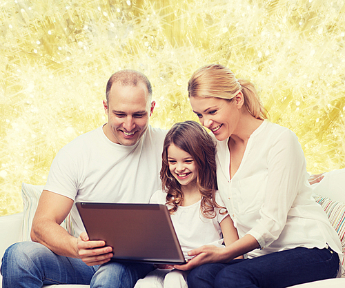 family, childhood, holidays, technology and people concept - smiling family with laptop computer over golden lights background