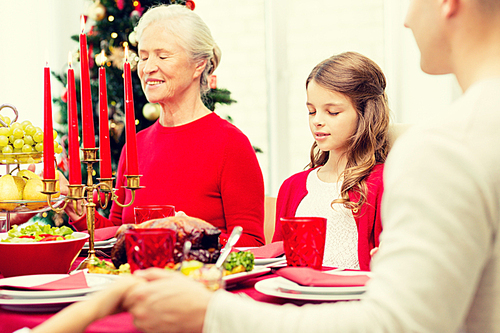 family, holidays, generation, christmas and people concept - smiling family having dinner and praying at home