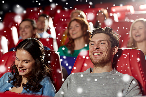 cinema, entertainment and people concept - happy friends watching comedy movie in theater with snowflakes
