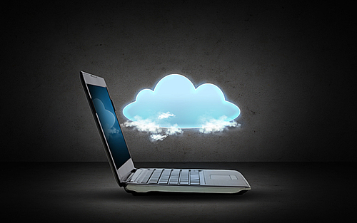 technology, cloud computing and data transfer concept - open laptop computer with cloud projection over dark gray background