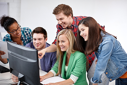 education, people, friendship, technology and learning concept - group of happy international high school students or classmates in computer class