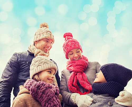 family, childhood, season and people concept - happy family in winter clothes over blue lights background