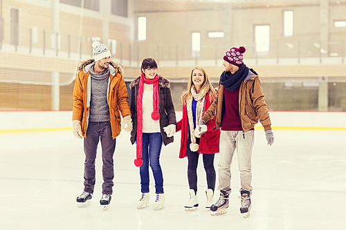 people, friendship, sport and leisure concept - happy friends on skating rink