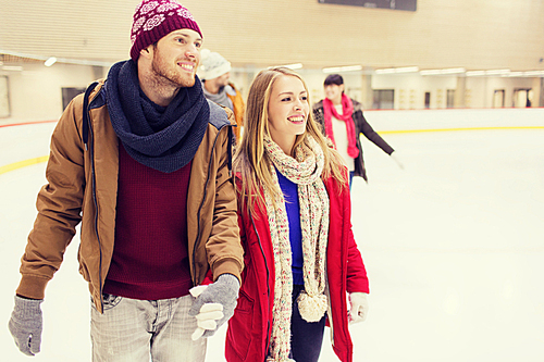 people, friendship, sport and leisure concept - happy friends on skating rink