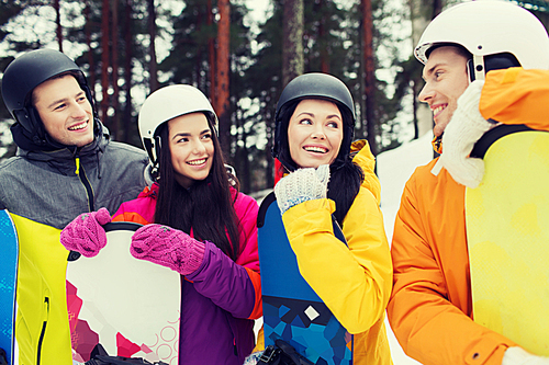 winter, leisure, extreme sport, friendship and people concept - happy friends in helmets with snowboards talking