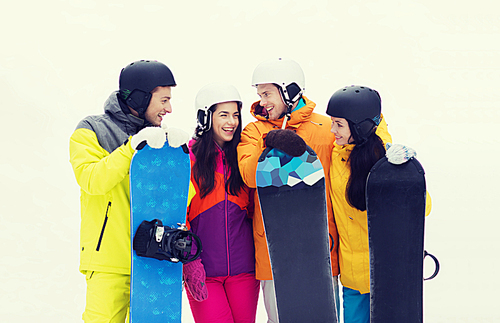 winter, leisure, extreme sport, friendship and people concept - happy friends in helmets with snowboards talking