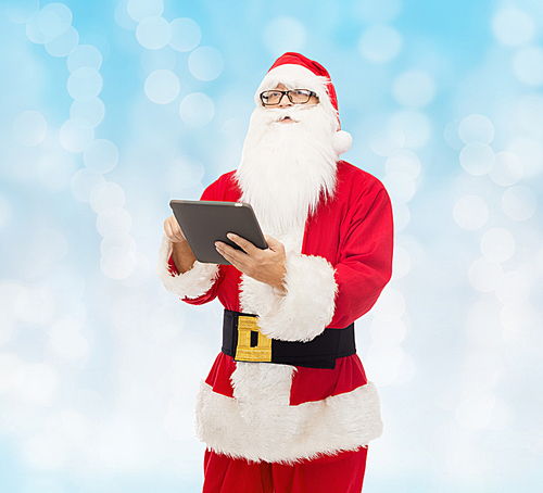 christmas, holidays, technology and people concept - man in costume of santa claus with tablet pc computer over blue lights background