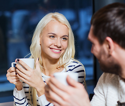 people, leisure, communication, eating and drinking concept - happy couple meeting and drinking tea or coffee at cafe