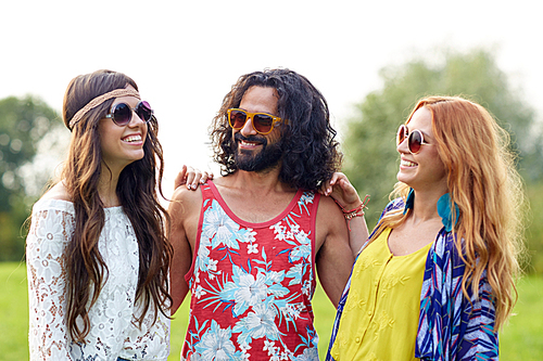 nature, summer, youth culture and people concept - smiling young hippie friends in sunglasses talking outdoors