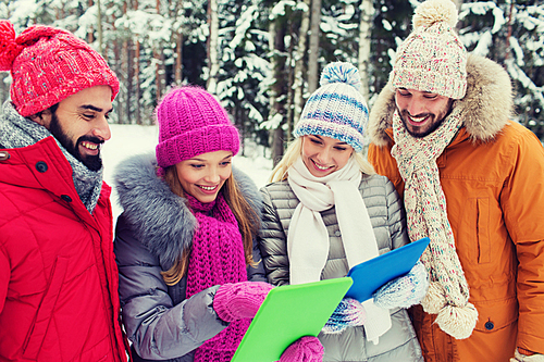 technology, season, friendship and people concept - group of smiling men and women with tablet pc computers in winter forest