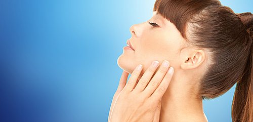 beauty, people, body care and health concept - beautiful young woman face over blue background