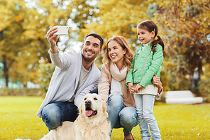 family, pet, season, technology and people concept - happy family with labrador retriever dog taking selfie by smartphone in autumnl park