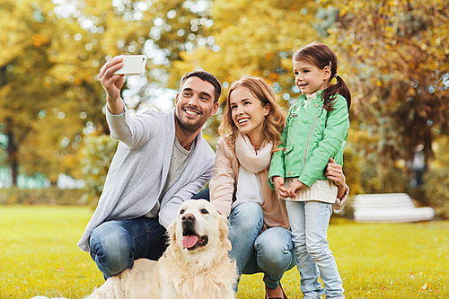 family, pet, season, technology and people concept - happy family with labrador retriever dog taking selfie by smartphone in autumnl park