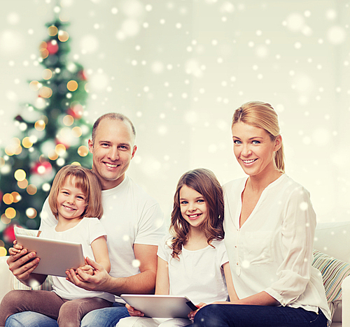 family, holidays, technology and people - smiling mother, father and little girls with tablet pc computers at home