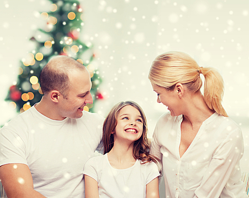 family, childhood, holidays and people - smiling mother, father and little girl over living room and christmas tree background