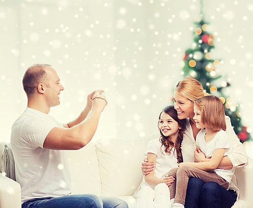 family, holidays, technology and people - smiling mother, father and little girls with camera photographing at home