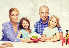 food, family, children, happiness and people concept - happy family with two kids showing salad in bowl at home