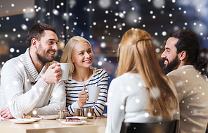 people, leisure, communication, season and concept - happy friends meeting and drinking tea or coffee at winter cafe
