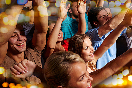 party, holidays, celebration, nightlife and people concept - group of smiling friends waving hands at concert in club