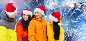 winter holidays, christmas, friendship and people concept - happy friends in santa hats and ski suits over firework background