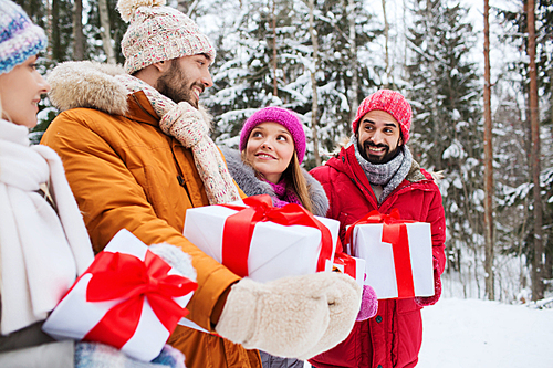 holidays, christmas, season, friendship and people concept - group of smiling friends with gift boxes in winter forest