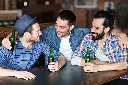 people, leisure, friendship and bachelor party concept - happy male friends drinking bottled beer and talking at bar or pub