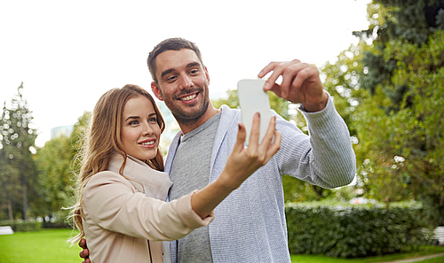 love, relationship, technology and people concept - happy couple with smartphone taking selfie in summer park