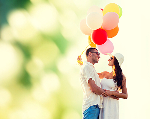 love, wedding, summer, dating and people concept - smiling couple wearing sunglasses with balloons hugging over green background