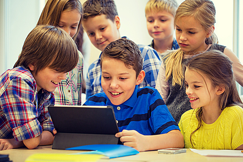 education, elementary school, learning, technology and people concept - group of school kids with tablet pc computer having fun on break in classroom