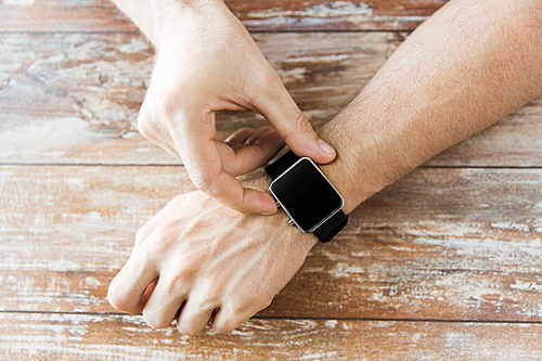 business, technology and people concept - close up of male hands setting smart watch at home