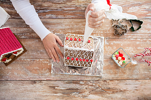 cooking, people, christmas and decoration concept - close up of happy woman making gingerbread houses at home