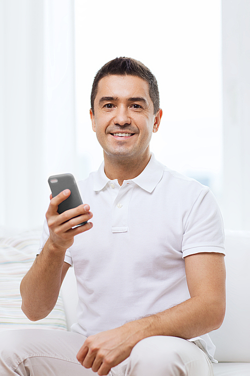 technology, people, lifestyle and communication concept - happy man with smartphone at home