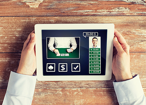 casino, online gambling, technology and people concept - close up of poker player with tablet pc computer at table