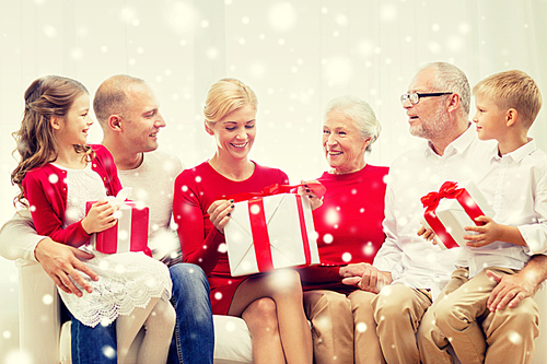 family, holidays, generation, christmas and people concept - smiling family with gift boxes sitting on couch at home