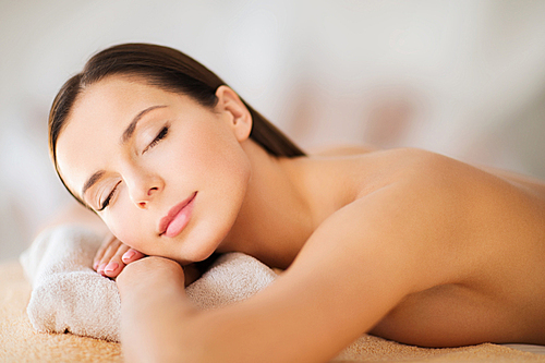 health and beauty, resort and relaxation concept - beautiful woman with closed eyes in spa salon lying on the massage desk