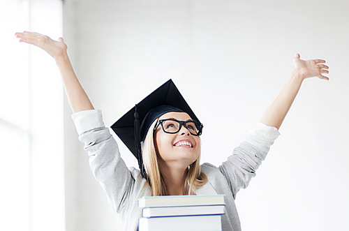 happy student in graduation cap with stack of books