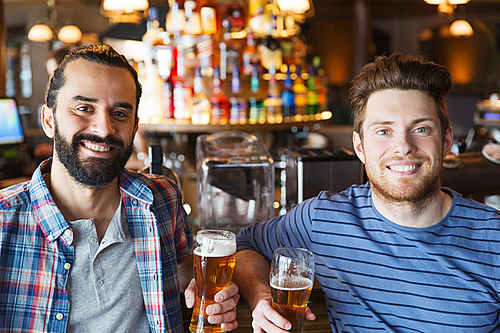 people, leisure, friendship and bachelor party concept - happy male friends drinking beer and talking at bar or pub