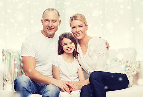 family, childhood, people and home concept - smiling parents with little girl sitting and hugging at home