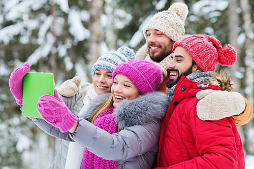 technology, season, friendship and people concept - group of smiling men and women taking selfie tablet pc computer in winter forest