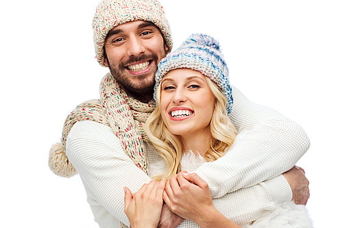 winter, fashion, couple, christmas and people concept - smiling man and woman in hats and scarf hugging